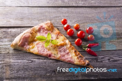 Pizza Cut On Wooden Table, Cherry Tomato And Hot Peppers Stock Photo