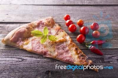 Pizza Cut On Wooden Table, Cherry Tomato And Hot Peppers Stock Photo