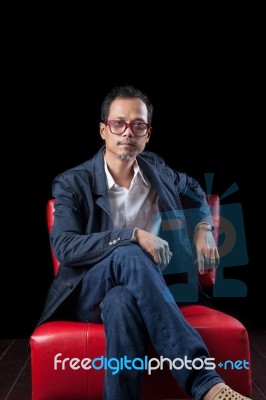 Portrait Face Of 45s Years Old Asian Man Sitting On Red Sofa In Stock Photo