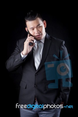 Portrait Of Asian Business Man Talking Mobile Phone Against Blac… Stock Photo