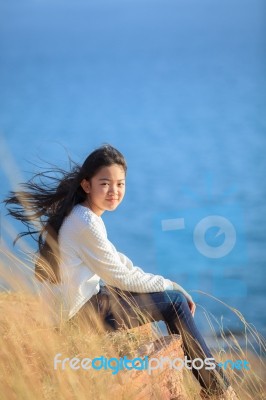 Portrait Of Asian Girl Relaxing Emotion Sitting In Grass Field And Windy Evening Use For Teen Age Leisure And Activities Traveling Vacation Time Stock Photo