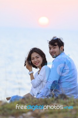 Portrait Of Asian Younger Man And Woman Relaxing Vacation At Sea Side Happiness Emotion Against Sun Set Sky Background Stock Photo