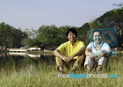 Portrait Of Beautiful Couple Sitting On Grass Stock Photo