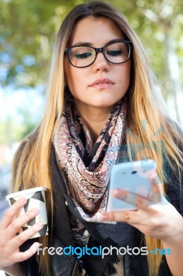 Portrait Of Beautiful Girl Drinking Coffee And Using Her Mobile Stock Photo