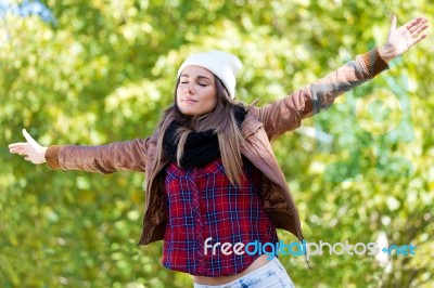 Portrait Of Beautiful Girl Standing In Autumn Field With Arms Ra… Stock Photo