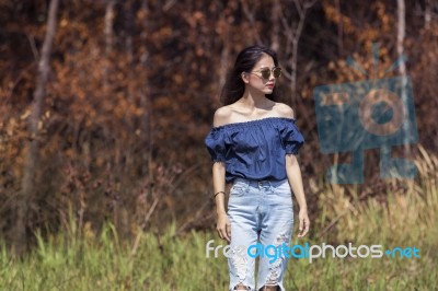 Portrait Of Beautiful Young Asian Woman Standing Against Dry Plant On Grass Field Stock Photo