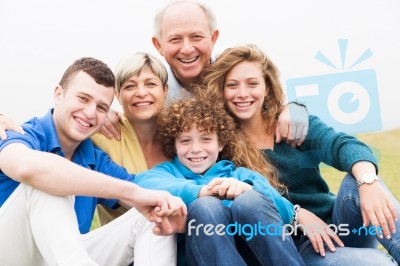 Portrait Of Family Sitting On Beach Lawn Stock Photo