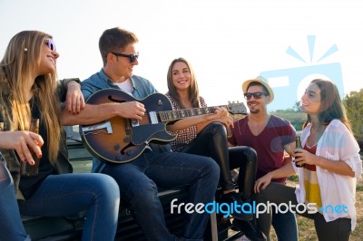 Portrait Of Group Of Friends Playing Guitar And Drinking Beer Stock Photo