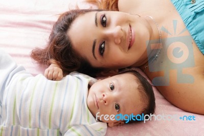 Portrait Of Happy Young Attractive Hispanic Mother Lying With He… Stock Photo