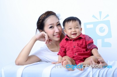 Portrait Of Laughing Asian Mother And Sitting Baby On Bench Stock Photo