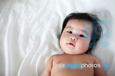 Portrait Of Newborn Baby Lying Down On A Bed, Top View Stock Photo