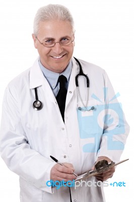 Portrait Of Senior Doctor Writing Reports Stock Photo