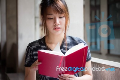 Portrait Of Thai Adult Beautiful Girl Reading Red Book Stock Photo