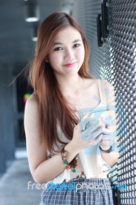 Portrait Of Thai Adult Beautiful Girl Using Her Smart Phone And Smile Stock Photo