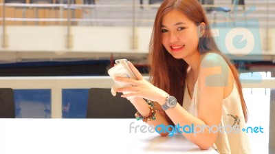 Portrait Of Thai Adult Beautiful Girl Using Her Smart Phone And Smile Stock Photo