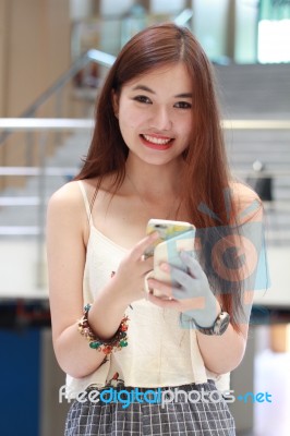 Portrait Of Thai Adult Beautiful Girl Using Her Smart Phone And Smile Stock Photo