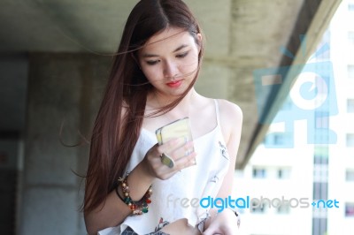 Portrait Of Thai Adult Beautiful Girl Using Her Smart Phone And Smile Stock Photo