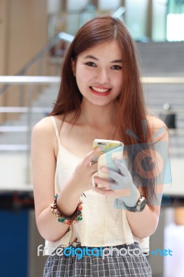 Portrait Of Thai Adult Beautiful Girl Using Her Smart Phone And Smile Stock Photo