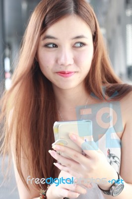 Portrait Of Thai Adult Beautiful Girl Using Her Smart Phone And Smile Stock Photo