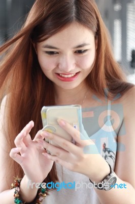 Portrait Of Thai Adult Beautiful Girl Using Her Smart Phone And Smile Stock Photo