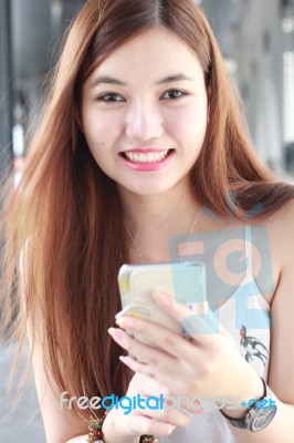 Portrait Of Thai Adult Beautiful Girl Using Her Smart Phone And Smile Stock Photo