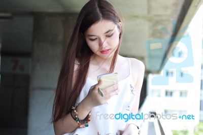 Portrait Of Thai Adult Beautiful Girl Using Her Smart Phone And Smile Stock Photo