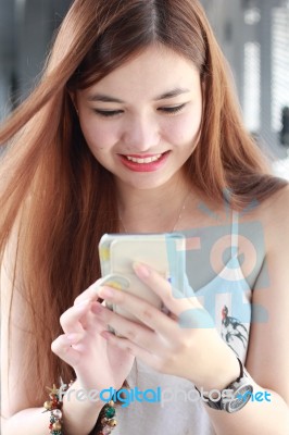 Portrait Of Thai Adult Beautiful Girl Using Her Smart Phone And Smile Stock Photo