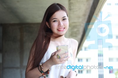 Portrait Of Thai Adult Beautiful Girl Using Her Smart Phone And Smile Stock Photo