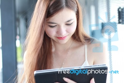 Portrait Of Thai Adult Beautiful Girl Using Her Tablet And Smile In University Stock Photo