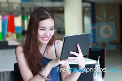 Portrait Of Thai Adult Beautiful Girl Using Her Tablet And Smile In University Stock Photo