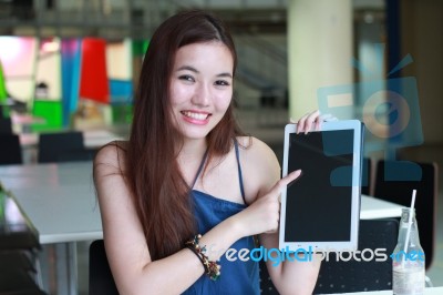 Portrait Of Thai Adult Beautiful Girl Using Her Tablet And Smile In University Stock Photo