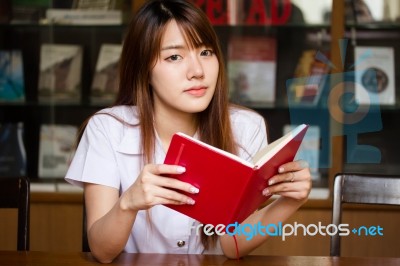 Portrait Of Thai Adult Student University Uniform Beautiful Girl Reading Red Book Stock Photo