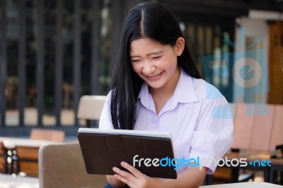 Portrait Of Thai High School Student Uniform Beautiful Girl Using Her Tablet Stock Photo