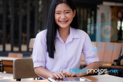 Portrait Of Thai High School Student Uniform Beautiful Girl Using Her Tablet Stock Photo