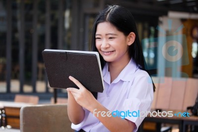 Portrait Of Thai High School Student Uniform Beautiful Girl Using Her Tablet Stock Photo