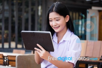 Portrait Of Thai High School Student Uniform Beautiful Girl Using Her Tablet Stock Photo