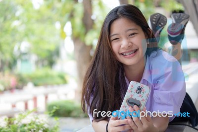 Portrait Of Thai High School Student Uniform Teen Beautiful Girl Using Her Phone And Smile Stock Photo