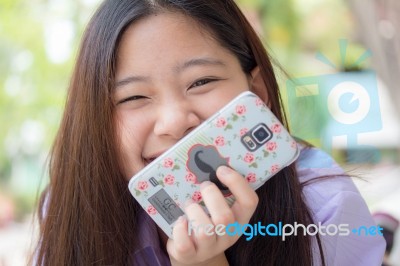 Portrait Of Thai High School Student Uniform Teen Beautiful Girl Using Her Phone And Smile Stock Photo