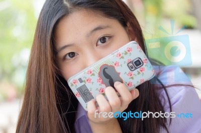 Portrait Of Thai High School Student Uniform Teen Beautiful Girl Using Her Phone And Smile Stock Photo