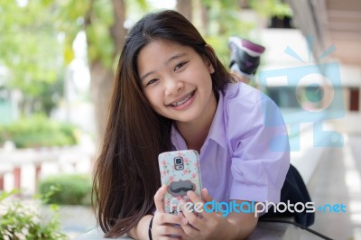 Portrait Of Thai High School Student Uniform Teen Beautiful Girl Using Her Phone And Smile Stock Photo