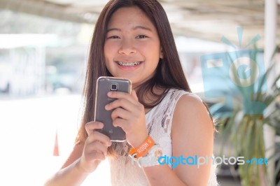 Portrait Of Thai Student Teen Beautiful Girl Using Her Phone And Smile Stock Photo