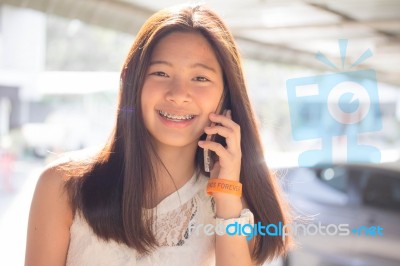 Portrait Of Thai Student Teen Beautiful Girl Using Her Phone And Smile Stock Photo