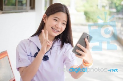 Portrait Of Thai Student Teen Beautiful Girl Using Her Phone And Smile Stock Photo