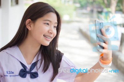 Portrait Of Thai Student Teen Beautiful Girl Using Her Phone And Smile Stock Photo