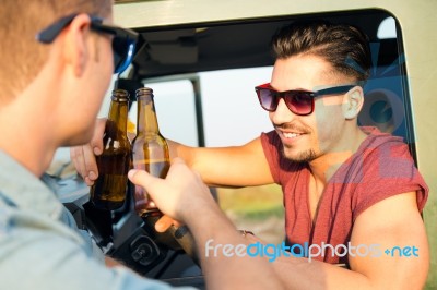 Portrait Of Two Friends Toasting With Bottles Of Beer In Car Stock Photo