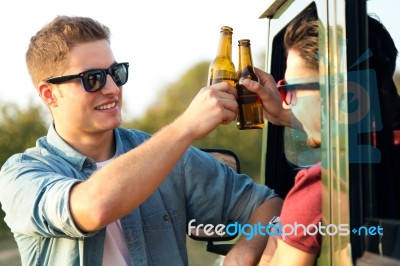 Portrait Of Two Friends Toasting With Bottles Of Beer In Car Stock Photo