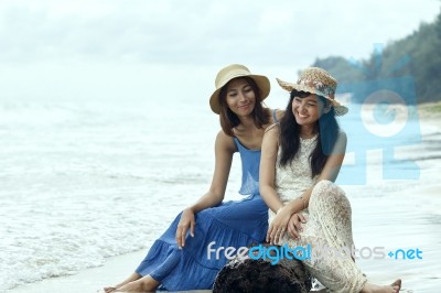 Portrait Of Young Beautiful Asian Tan Skin Woman Wearing Fashion Straw Hat Sitting On Wood Lock At Sea Beach With Relaxing Emotion Stock Photo