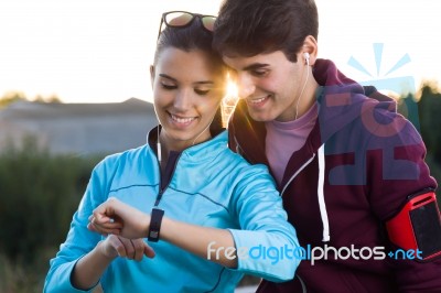 Portrait Of Young Couple Using They Smartwatch After Running Stock Photo