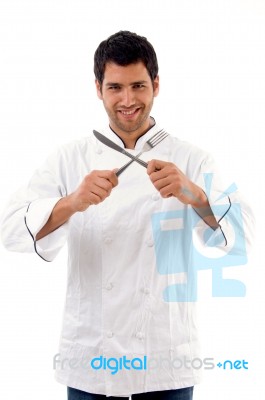 Portrait Of Young Male Chef Holding Fork And Knife Stock Photo