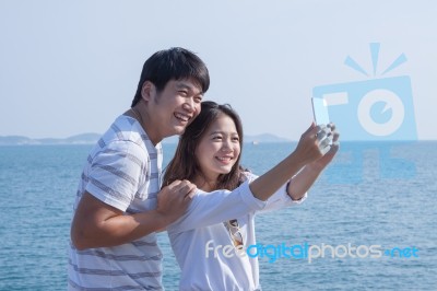 Portrait Of Young Man And Woman Selfie ,self Portrait By Mobile Phone In Relaxing Emotion Sea Beach Destination Use For People In Modern Life Style Stock Photo